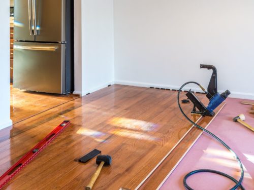man installing hardwood over carpet