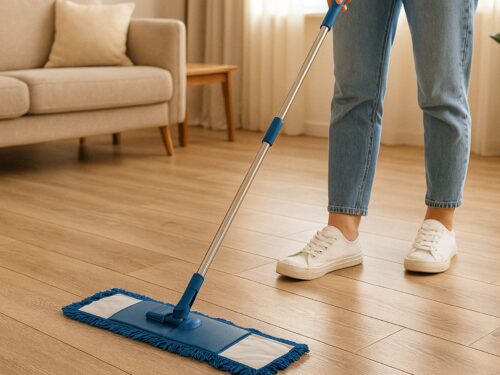 Photo of a modern home with someone mopping LVP flooring using a microfiber mop, surrounded by natural light and neutral-toned furniture.